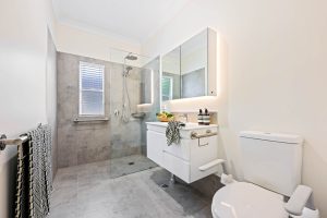 A newly renovated bathroom in Wauchope NSW with slate grey tiling, featuring a new walk in shower and vanity.