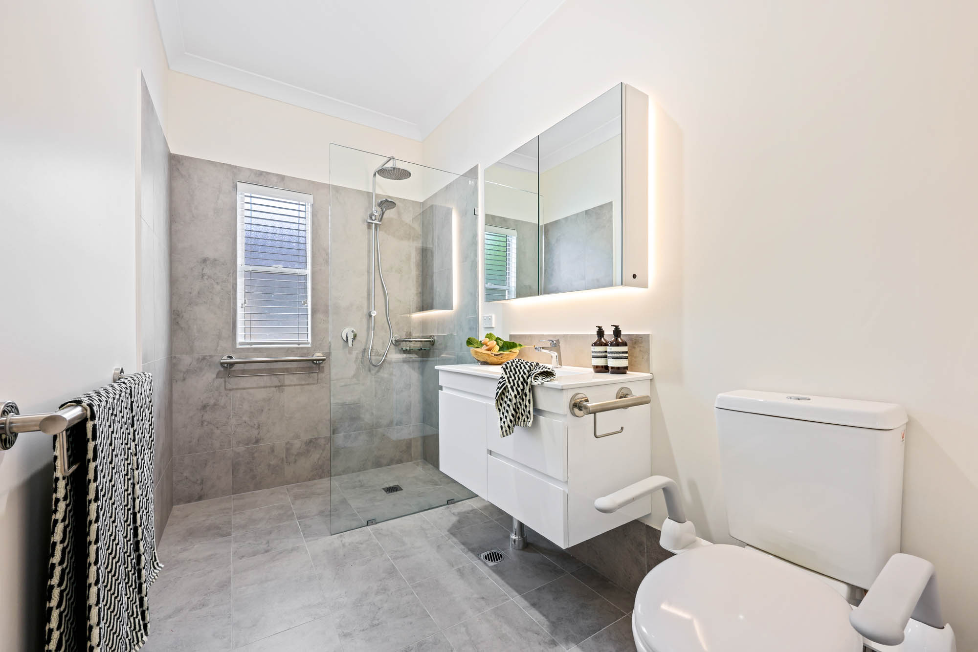 A newly renovated bathroom in Wauchope NSW with slate grey tiling, featuring a new walk in shower and vanity.